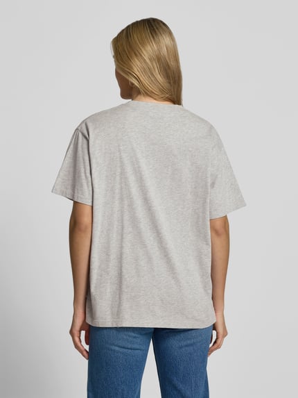 Vrouwenmodel draagt Relaxed Fit T-Shirt uit puur katoen van Anine Bing, lichte effen kleur, labelprint, ronde hals, ruglengte maat S 63 cm, korte mouwen, ganzkörperansicht rugaanzicht.
