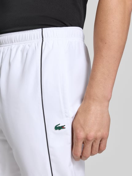 Männermodel trägt weiße Regular Fit Trainingshose mit Logo-Patch von Lacoste, Herren Trainingshose, Nahaufnahme Hüfte.