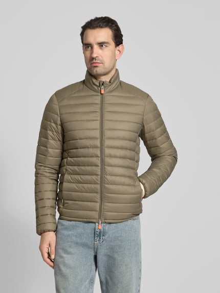 Männermodel trägt Steppjacke mit Zweiwegereißverschluss Modell 'Alexander' von SAVE THE DUCK in Olivgrün, Regular Fit, Ganzkörperansicht von vorne.
