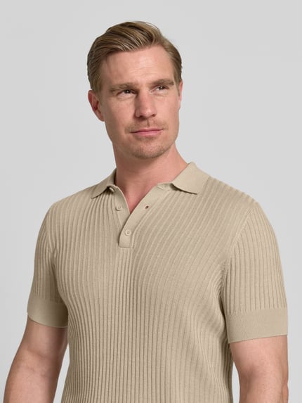 Männermodel trägt Slim Fit Poloshirt aus Viskose-Mix von Antony Morato in Beige, Strick-Optik, Polokragen, Kurzärmelig, Nahaufnahme Oberkörper.