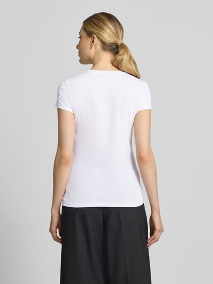 Frauenmodel trägt Slim Fit T-Shirt aus Baumwolle von Armani Exchange in Weiß, Rundhalsausschnitt, Rückenlänge 59 cm, Ganzkörperansicht Rückansicht.