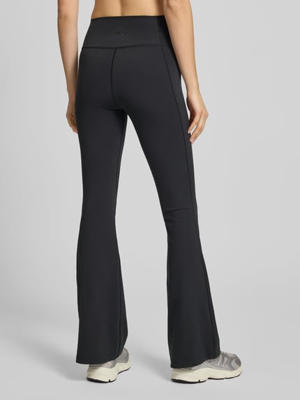 Frauenmodel trägt Flared Fit Stoffhose mit breitem Bund Modell 'All Me' von adidas Sportswear, schwarz, glatte Oberfläche, Ganzkörperansicht Rückansicht.