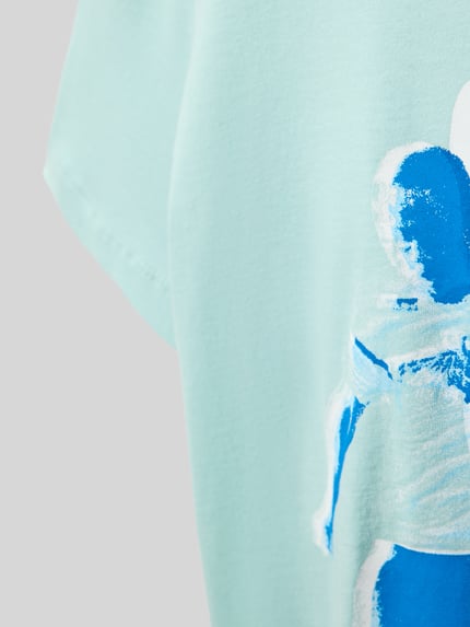 Mädchen trägt Regular Fit T-Shirt aus reiner Baumwolle von s.Oliver RED LABEL, Optik: Unifarben, Motiv-Print, Nahaufnahme Oberkörper.