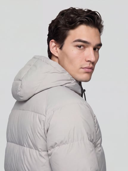 Männermodel trägt Steppjacke mit Kapuze von Nike in Unifarbe mit strukturierter Webware und Logo-Print, Nahaufnahme Oberkörper.