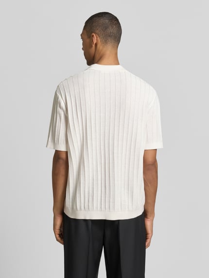 Männermodel trägt Regular Fit Poloshirt aus Baumwoll-Strick Modell 'DANE' von SELECTED HOMME, Optik: Unifarben, Struktur-Muster, Ganzkörperansicht Rückansicht.