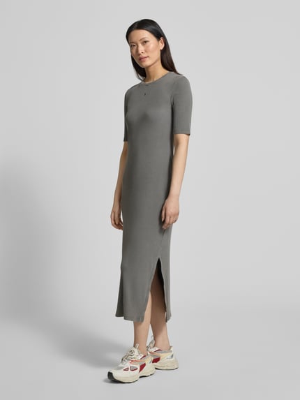 Frauenmodel trägt körpernahes Freizeitkleid aus Baumwoll-Mix Modell 'SEHAARAA' von Armedangels in Used Look, Midi-Länge, Rundhalsausschnitt, kurzarm, Seitenschlitz, Rippstruktur, Label Stitching, graue Farbe, Ganzkörperansicht von vorne.
