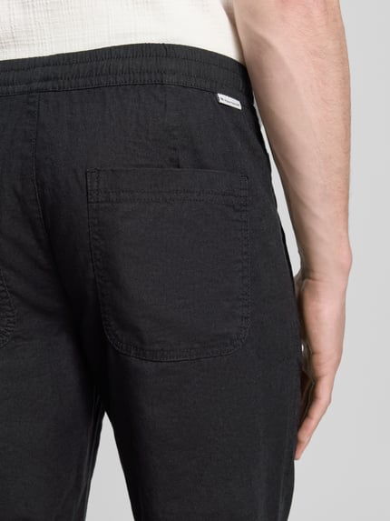 Männermodel trägt Gerade Hose aus Leinen-Baumwoll-Mix von Tom Tailor, efekt: jednolity kolor, naszywka z logo, mieszanka lnu i bawełny, wpuszczane kieszenie, kieszeń z tyłu, zapięcie na guzik i zamek błyskawiczny, Ganzkörperansicht Rückansicht.
