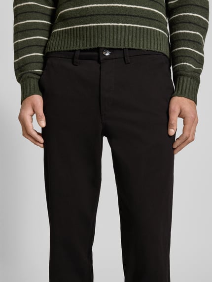Mężczyzna nosi Straight Fit Chino mit Gesäßtaschen Modell 'Stollie' od Jack & Jones, elastyczna mieszanka bawełny, szerokość w rozmiarze 32/32: 44 cm, długość nogawki od wewnątrz: 75 cm, detal ubrania, zbliżenie na przednią część spodni.