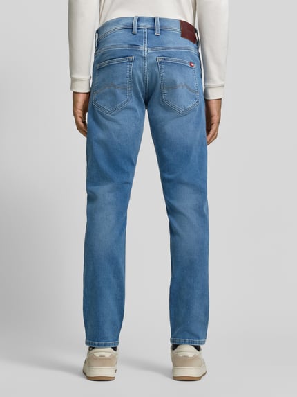 Männermodel trägt Regular Fit Jeans mit Used Waschung von MUSTANG in Denim-Optik, Medium Wash mit Whiskering, Ganzkörperansicht Rückansicht.