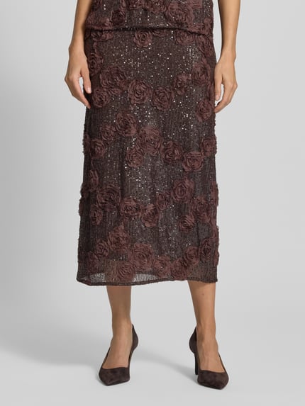 Frauenmodel trägt Midirock mit Pailletten Modell 'ELYSIA' von YAS, brauner Material-Mix mit Blumenstruktur, Nahaufnahme Unterkörper.
