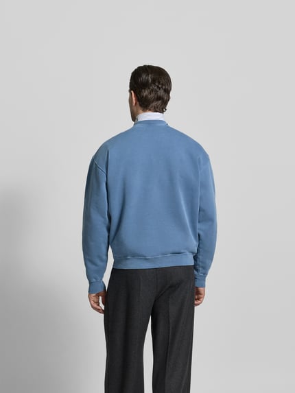 Männermodel trägt Regular Fit Sweatshirt mit Logo-Detail von Dsquared2 aus reiner Baumwolle in Blau, Rückenlänge 64 cm, Ganzkörperansicht Rückansicht.