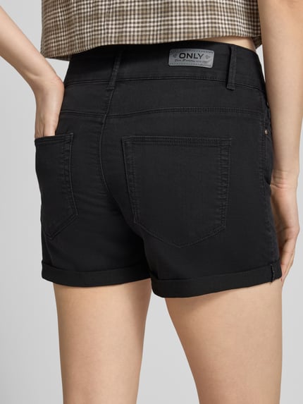 Frauenmodel trägt Regular Fit Jeansshorts aus Baumwoll-Mix Modell 'CARMEN' von Only in Schwarz mit Label Patch, 5-Pocket-Design, Ganzkörperansicht Rückansicht.