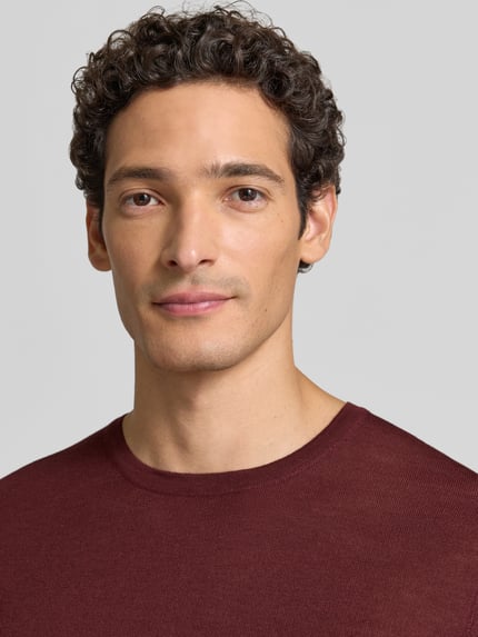 Männermodel trägt Strickpullover aus Schurwolle mit Rundhalsausschnitt von MAERZ Muenchen in Bordeaux, Nahaufnahme Oberkörper, Regular Fit