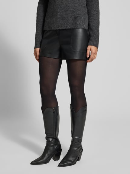 Frauenmodel trägt Baggy Fit Bermuda in Leder-Optik Modell 'TRICIA' von ONLY, schwarz glänzend, kombiniert mit Stiefeln, Nahaufnahme Unterkörper, Damen Bermuda von ONLY.