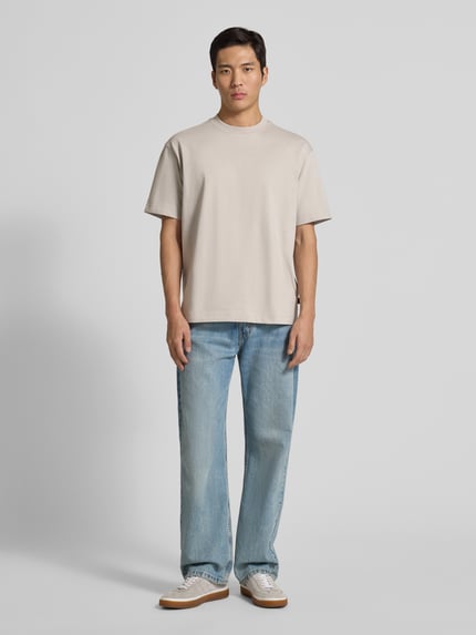 Männermodel trägt Regular Fit T-Shirt aus Baumwoll-Mix Modell 'TEETIM' von BOSS Orange, Optik: Unifarben, Label-Print, Rundhals, Ganzkörperansicht von vorne.