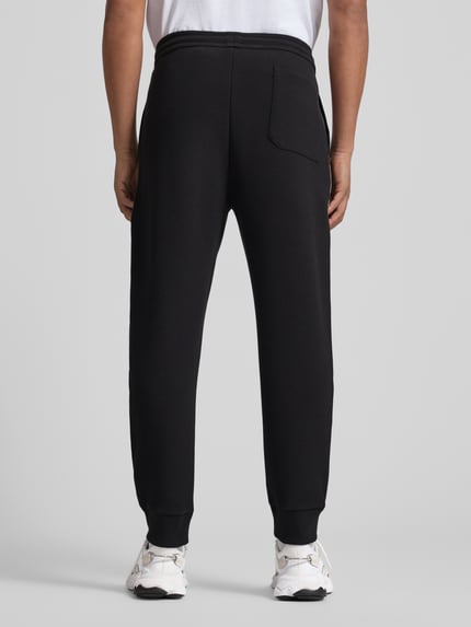 Männermodel trägt Regular Fit Sweatpants aus Baumwoll-Mix Modell 'JOIN HADIKO' von BOSS Green, Optik: Unifarben, Piqué, Ganzkörperansicht Rückansicht.