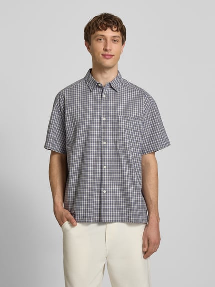 Männermodel trägt Loose Fit Freizeithemd aus reiner Baumwolle Modell 'DAVES' von Only & Sons mit kariertem Allover-Muster, Ganzkörperansicht von vorne.