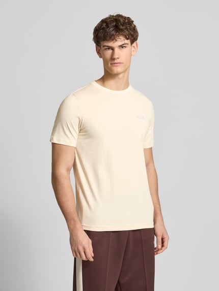Männermodel trägt T-Shirt aus reiner Baumwolle von PUMA PERFORMANCE in Beige mit Rundhalsausschnitt, gerader Schnitt, Ganzkörperansicht von vorne.