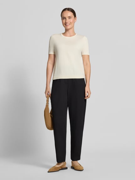 Frauenmodel trägt schwarze Relaxed Fit Anzughose mit Bundfalten Modell 'SC-SIHAM 103' von Soyaconcept, helle Wand, Ganzkörperansicht von vorne. Damen Anzughose von Soyaconcept.