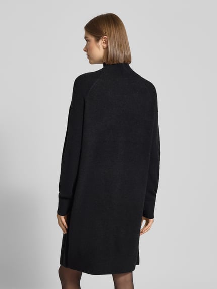 Frauenmodel trägt Oversized Strickkleid aus Schurwoll-Mix von Marc O'Polo Denim in Schwarz, Feinstrick, gerippte Abschlüsse, Ganzkörperansicht Rückansicht.
