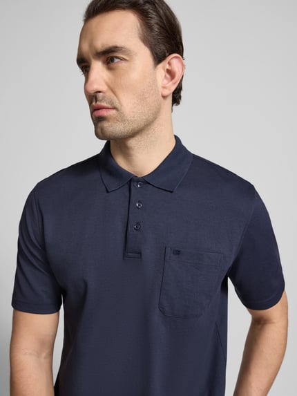 Männermodel trägt Regular Fit Poloshirt mit Brusttasche von Christian Berg Men in Dunkelblau, Baumwoll-Mix, Nahaufnahme Oberkörper.