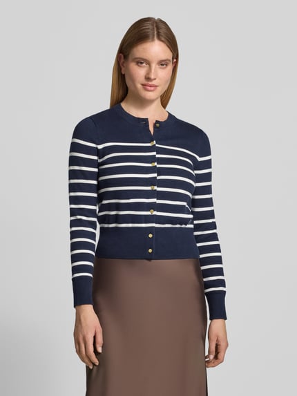Frauenmodel trägt Cardigan mit goldfarbenen Knöpfen von Tommy Hilfiger in Navy-Weiß, gestreifte Strickoptik, Regular Fit, Ganzkörperansicht von vorne.