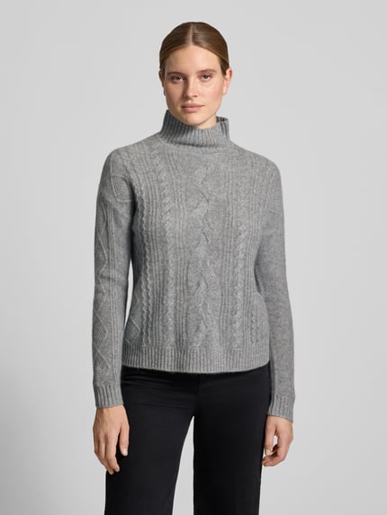 Vrouwenmodel draagt pullover van kasjmier met kabelpatroon van Christian Berg Woman, recht model, opstaande kraag, ribboorden, ruglengte maat S 57 cm, mouwlengte maat S 64 cm, grijze tinten, zachte textuur, gebreid motief, geheel lichaamsaanzicht van voren.