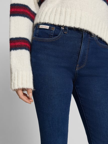 Frauenmodel trägt Skinny Fit Jeans mit 5-Pocket-Design von Calvin Klein Jeans in Dunkelblau, Baumwoll-Mix mit Stretch-Anteil, Nahaufnahme Oberkörper.