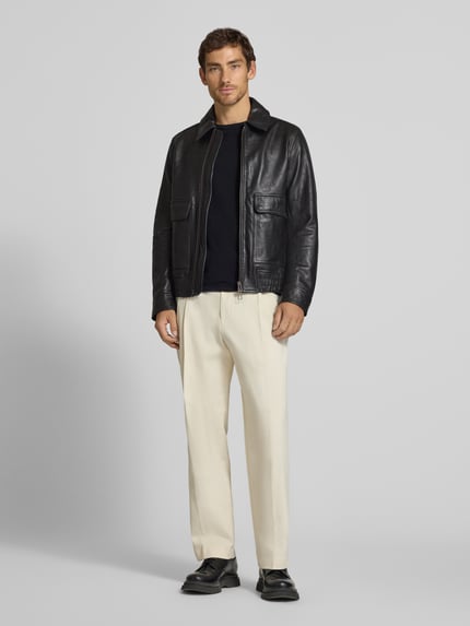 Männermodel trägt Lederjacke aus Schafsleder mit Pattentaschen von Paul Smith, Schwarz, seitliche Taschen, Bomber Fit, Ganzkörperansicht von vorne.