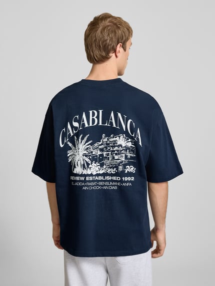 Männermodel trägt T-Shirt mit Label-Detail von REVIEW in Dunkelblau, Reine Baumwolle, Lockerer-Schnitt, Rundhalsausschnitt, 1/2-Arm, Rückenlänge 68 cm bei Größe M, Herren T-Shirt; Ganzkörperansicht Rückansicht.