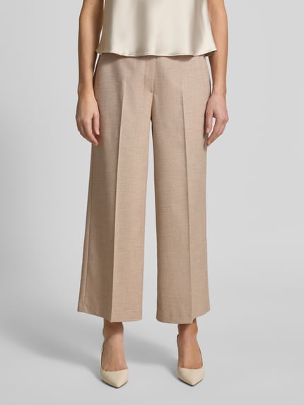 Vrouwenmodel draagt Fein strukturierte Hose mit Bügelfalten van More & More, beige, wijde fit, fijne structuur, viscosemix, volledige voorkant, detailopname bovenbenen.