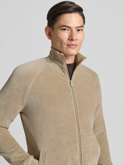 Männermodel trägt Sweatjacke mit Stehkragen von MCNEAL in Beige aus Baumwoll-Mix mit Reißverschluss, Nahaufnahme Oberkörper.