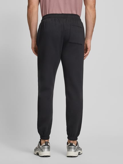 Männermodel trägt Sweatpants mit Logo und elastischem Bund von GAP, schwarze Farbe, Baumwoll-Mix, Regular-Fit, Ganzkörperansicht Rückansicht.