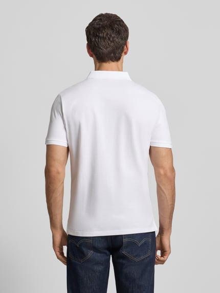 Männermodel trägt Regular Fit Poloshirt mit Logo-Stitching Modell 'BASIC' von Tom Tailor in Optik: Unifarben, Ganzkörperansicht Rückansicht.