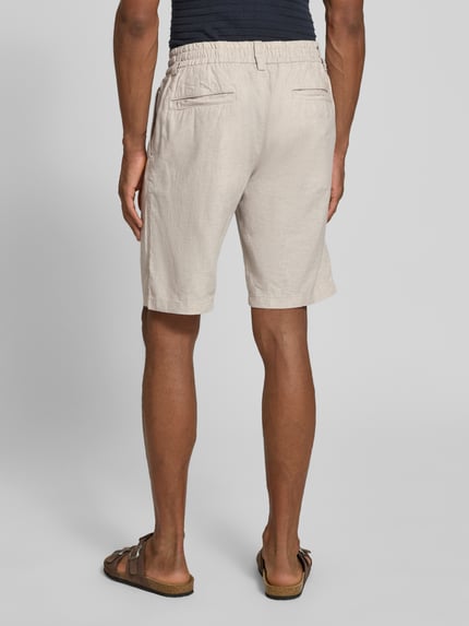 Mannenmodel draagt Tapered Chinoshorts uit linnenmix model 'DS_3S' van BOSS Orange, zandkleur, met boord, tunnelkoord, riemlussen, labelpatch, steekzakken, paspelzakken, materiaalverwerking: gevlamd garen, pasvorm: tapered fit, model: achteraanzicht volledige lichaamsfoto.