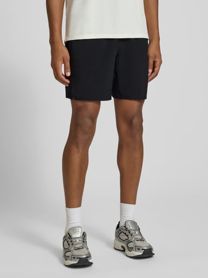 Męski model nosi szorty z elastycznym pasem i logo od ASICS, krój regular fit, Szerokość w rozmiarze M: 37 cm, Długość wewnętrzna nogawki M: 45 cm, widok całej sylwetki z przodu.