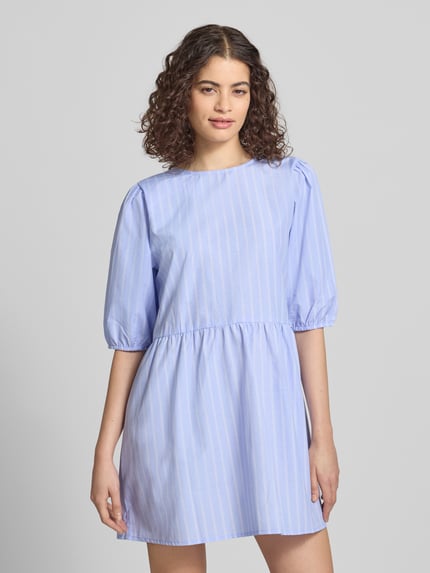 Kobiece modelka nosi sukienkę koszulową Relaxed Fit Blusenkleid mit Streifenmuster Modell 'CLARA TESSA' von Only, efekt: wzór w paski na całej powierzchni, długość mini, okrągły dekolt, bufiaste rękawy, krótkie rękawy, materiał: tkanina z recyklingu z dodatkiem bawełny, widok całej sylwetki z przodu.