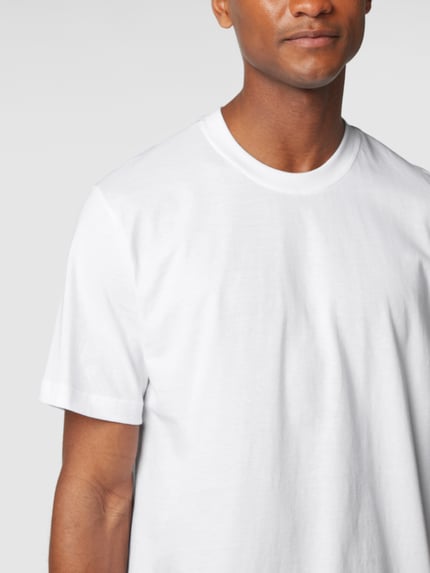 Mannenmodel draagt T-shirt met geribde ronde hals van Schiesser, puur katoen, regular fit, wit, zachte textuur. Nahaufnahme Oberkörper.