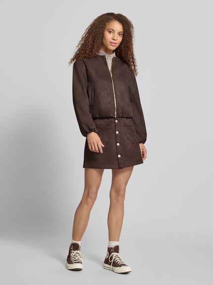 Kobiece model nosi Regular Fit kurtkę ze sztucznej skóry o wyglądzie zamszowym model 'STINA' od ONLY, ciemnobrązowy kolor, gładka faktura, damska kurtka skórzana od ONLY, widok całej sylwetki z przodu