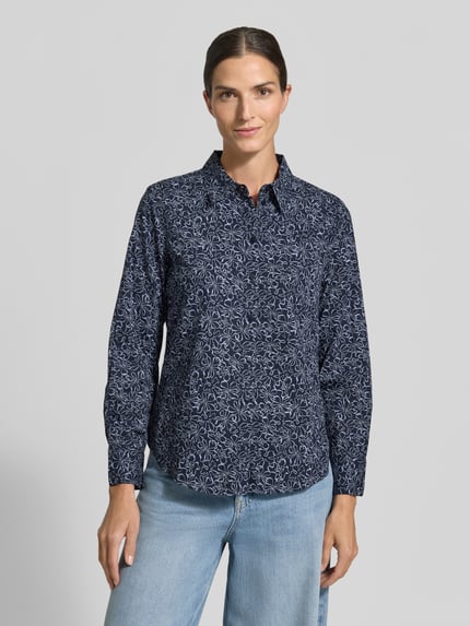 Frauenmodel trägt Langarmbluse mit abgerundetem Saum von Tom Tailor, florales Allover-Muster in Blau, Ganzkörperansicht von vorne.
