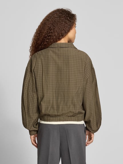Kobieta nosi Regular Fit Sweatjacke aus Viskose-Mix von adidas Originals w odcieniach oliwkowych i szarych, tekstura kratka, widok całej sylwetki od tyłu.