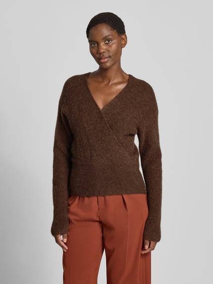 Frauenmodel trägt Strickpullover in Wickel-Optik Modell 'Bondie Hope' von MSCH Copenhagen, braun, V-Ausschnitt, Ganzkörperansicht von vorne. Mix mit Woll-Anteil, Regular Fit, Rückenlänge 50 cm, Ärmellänge 60 cm.