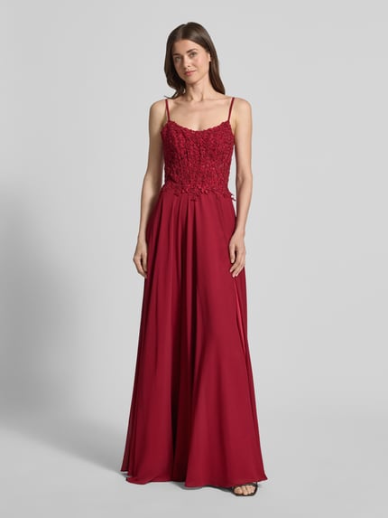 Frauenmodel trägt Abendkleid mit floralem Spitznbesatz von Mascara, bordeauxrot, tailliert, Chiffonrock, Carmen-Ausschnitt, Ganzkörperansicht von vorne.