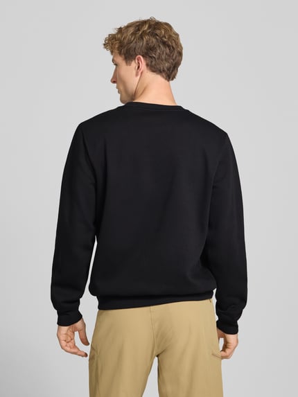 Männermodel trägt Regular Fit Sweatshirt Modell "EVOLUTION" van The North Face in zwart katoenmix, elastische boorden, ronde hals, ruglengte maat M 67 cm, mouwlengte maat M 69 cm, herensweatshirt, ganzkörperansicht rugaanzicht.
