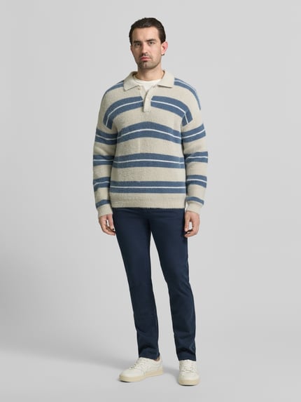 Männermodel trägt Slim Fit Chino aus Baumwoll-Mix Modell 'CHINO_SLIM' von BOSS Orange, feines Strukturmuster, Ganzkörperansicht von vorne.