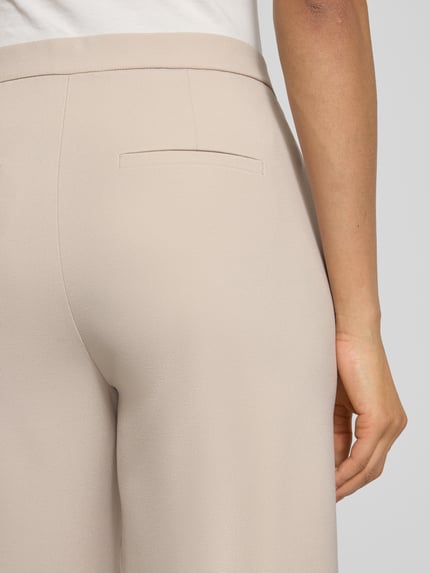 Frauenmodel trägt Wide Fit Schlupfhose mit Viskose-Anteil Modell 'Palina' von Raffaello Rossi, beige, Crêpe-Struktur, Detailaufnahme Rückansicht