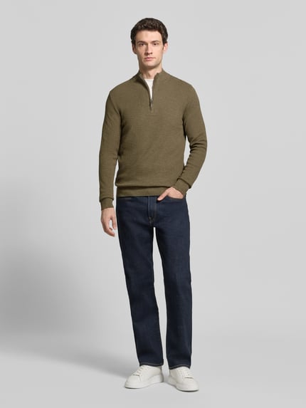 Männermodel trägt Slim Fit Strickpullover aus Baumwoll-Mix mit Troyer-Kragen von Profuomo, Olivgrün, elastische Abschlüsse, Ganzkörperansicht von vorne.