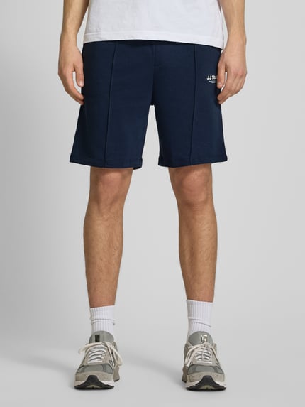 Männermodel trägt Sweatshorts mit Logo Modell 'KANE' von Jack & Jones in Dunkelblau, Baumwoll-Mix, Relaxed-Fit, Ganzkörperansicht von vorne.