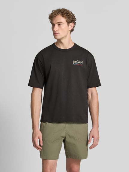 Männermodel trägt Relaxed Fit T-Shirt aus reiner Baumwolle von Polo Ralph Lauren in Schwarz mit Schriftzug, Ganzkörperansicht von vorne.