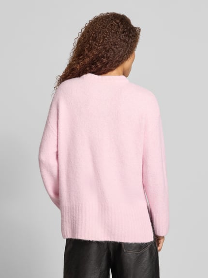 Frauenmodel trägt sweter z okrągłym dekoltem 'Pullover mit gerippten Abschlüssen' von PIECES, krój regular fit, jednokolorowy, długość longline, długi rękaw, prążkowane zakończenia rękawów i dołu, widoczna miękka tekstura, kolor jasnoróżowy, Ganzkörperansicht Rückansicht.